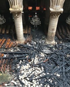 Aftermath of the devastating 2019 fire inside Notre-Dame Cathedral, showing charred beams and rubble scattered across the floor. Image source: Public Domain / News Coverage.